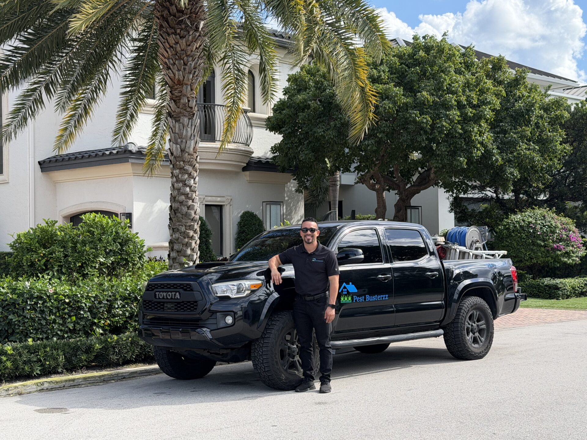 Pest Busterzz technician and service truck in front of a South Florida home